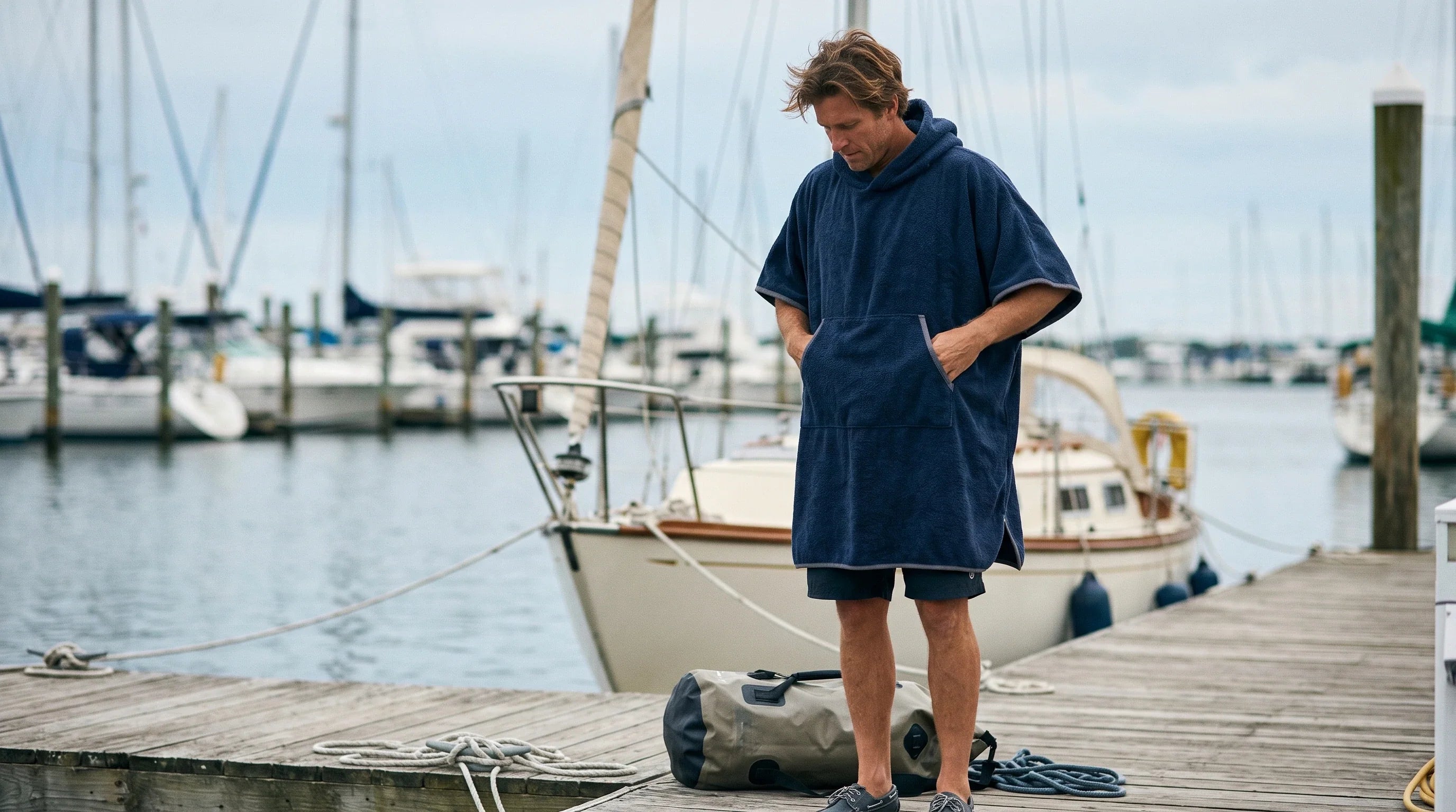 Una persona se cambia discretamente junto al puerto con un poncho náutico de secado rápido.